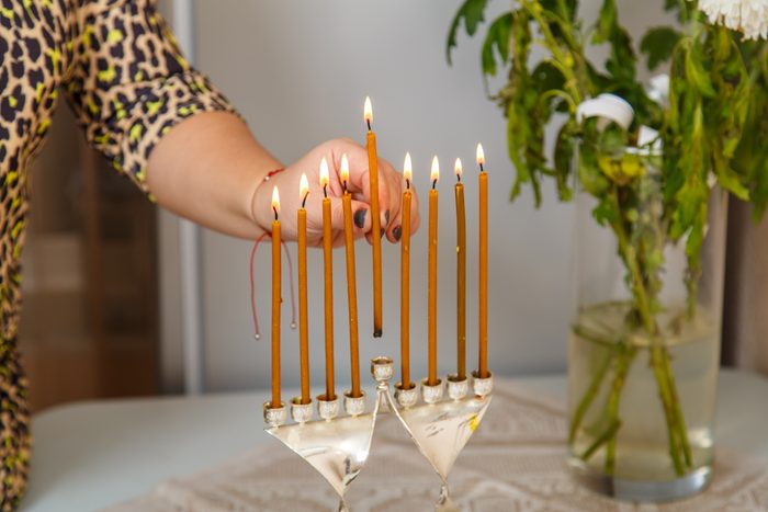 Midsection Of Woman lighting a menorah on a kitchen table