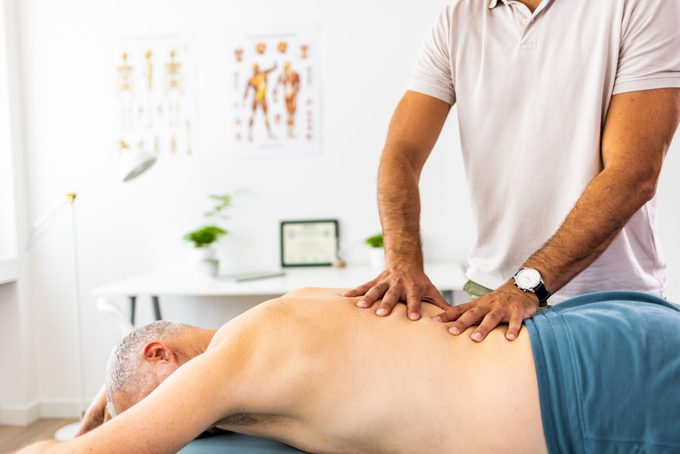Shot of a mature man lying face down and getting his back massaged by a physiotherapist at a clinic