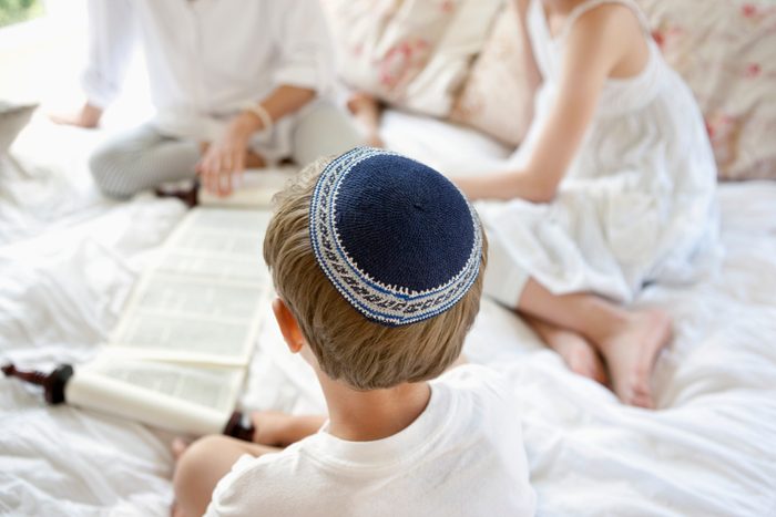 Boy wearing yarmulke and reading Torah scrolls