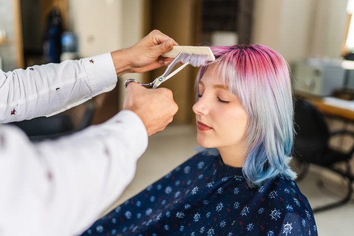 Young woman with colored hair getting a haircut at the hairdresser