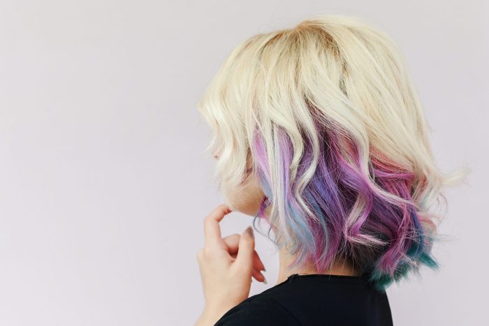 side view of imagined woman withcolorful hair looking at white wall