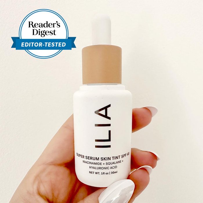 hand holding Ilia skin tint bottle with the Reader's digest editor tested badge in the upper left corner