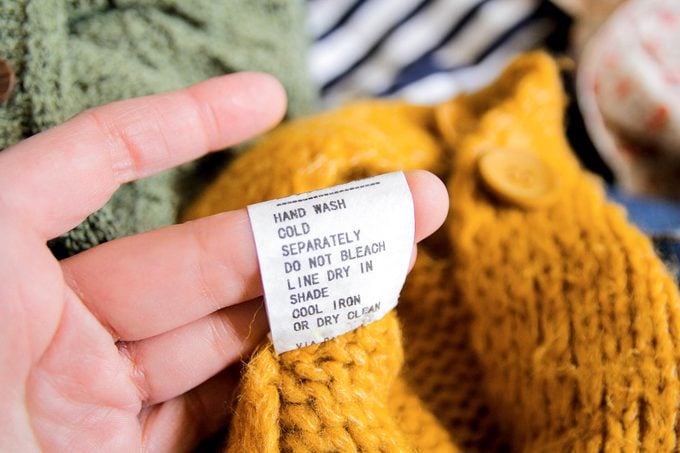 close up of a hand looking at washing instructions on a care label on a wool blanket