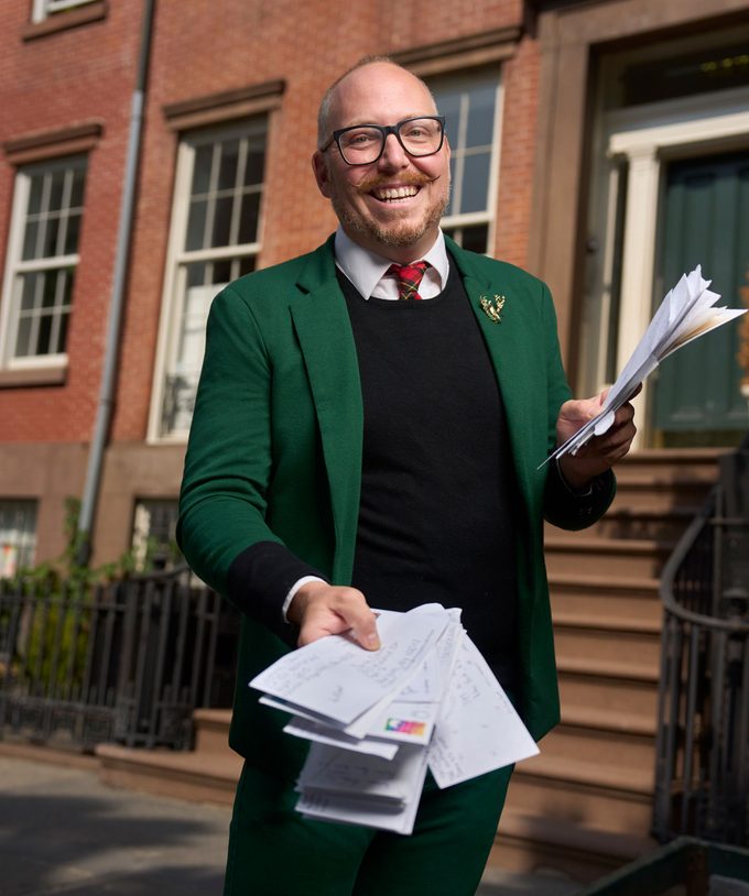 Jim Glaub holding letters in front of his apartment exterior