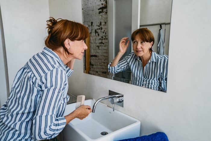 Senior woman adjusting hair in bathroom