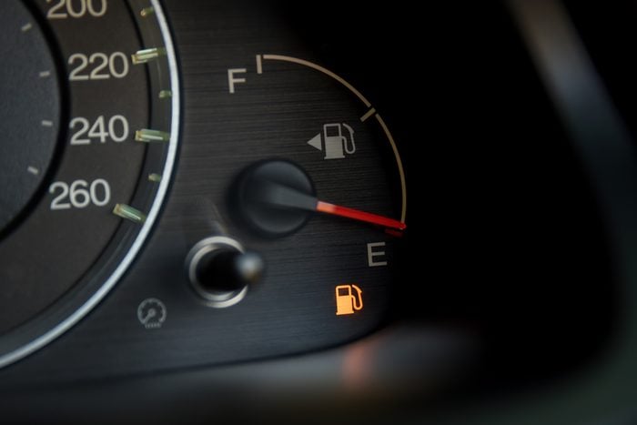 close up of a car dashboard gas indicator guage with the low fuel warning light lit