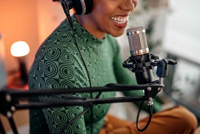 Smiling young woman recording podcast