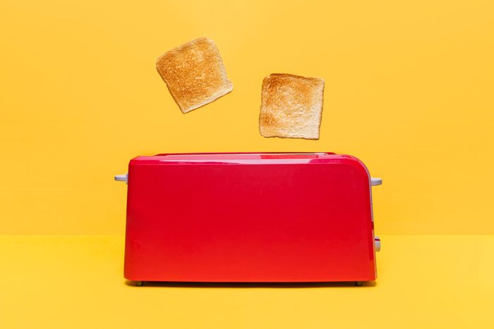 Red Toaster Toasting Two Bread Slices On Yellow Background