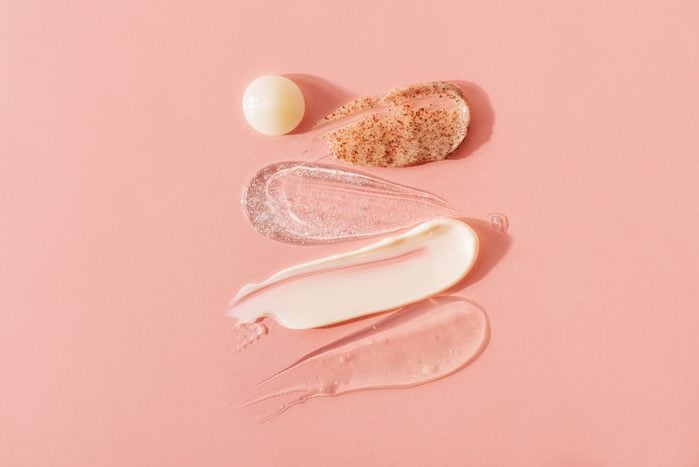 make up and skin care products spread on pink background