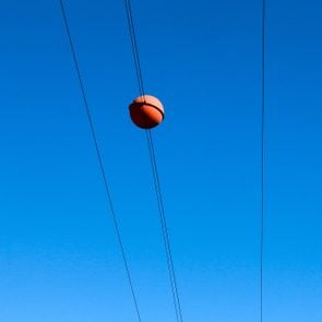 close up of a Red ball on power lines with blue sky in the background