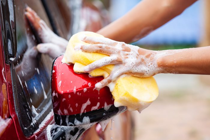 Man washing red car with sponge and soap