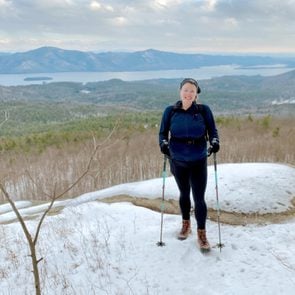 woman standing with snowshoes with mountain views in the background
