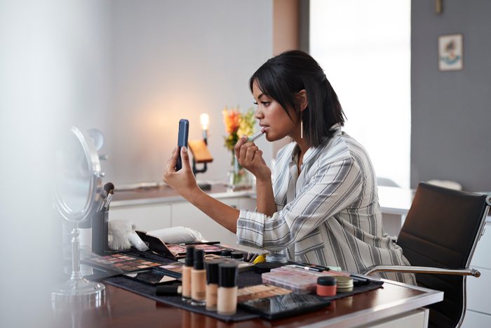 Female influencer recording make-up tip videos using smartphone, for her blog