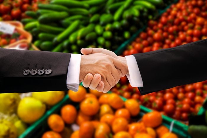 Businessman Shaking Hands in front of an assortment of vegetables and groceries