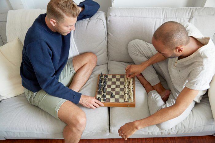 High angle view of men sitting on sofa playing chess smiling