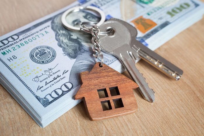 House Keys laying on American money on a wooden background