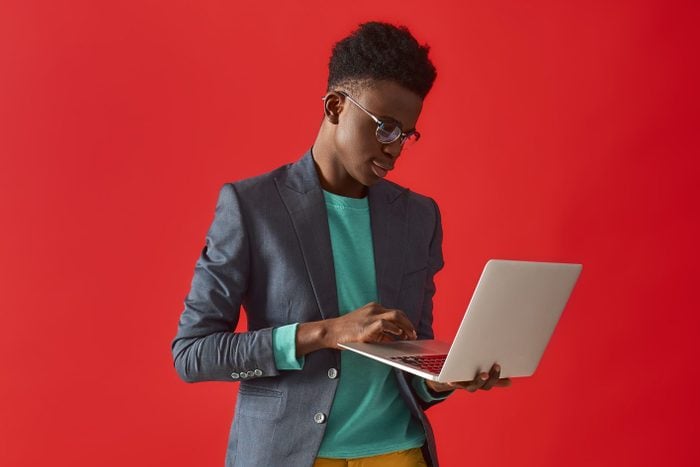 Молодой афроамериканец стоит с ноутбуком
