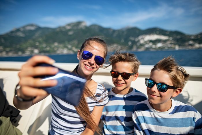 Three kids taking selfies on a boat near Amalfi coast, Italy
