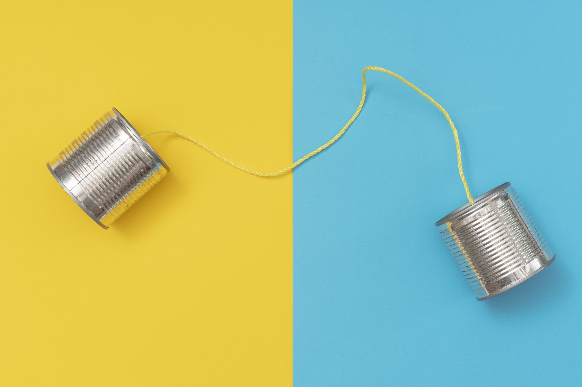 Tin can phone on yellow and blue paper backgrounds