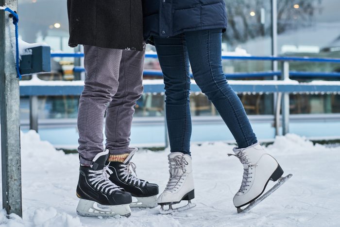 Happy couple dating in the ice rink, hugging and enjoying winter time