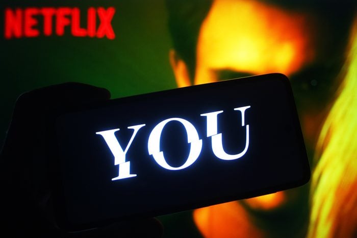 'You' logo of US Netflix show appears on a phone in front of Netflix loading screen