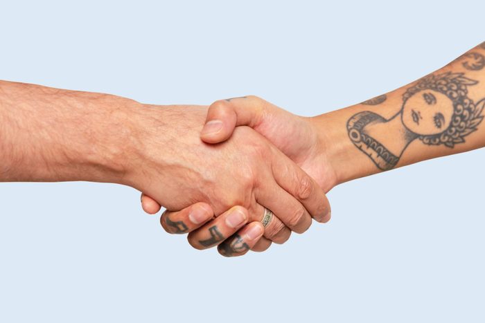 Cropped hands of male friends giving handshake against white background
