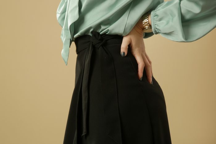 Close up of blouse tucked into skirt. Studio shot of woman waist.