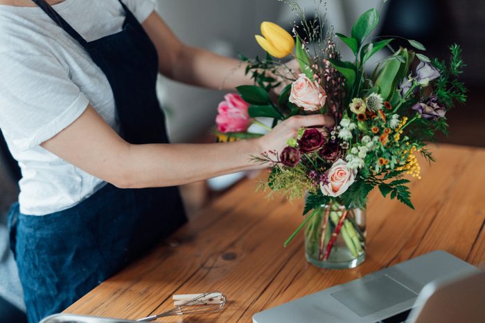 Cropped shot of young woman arranging fresh flowers at home