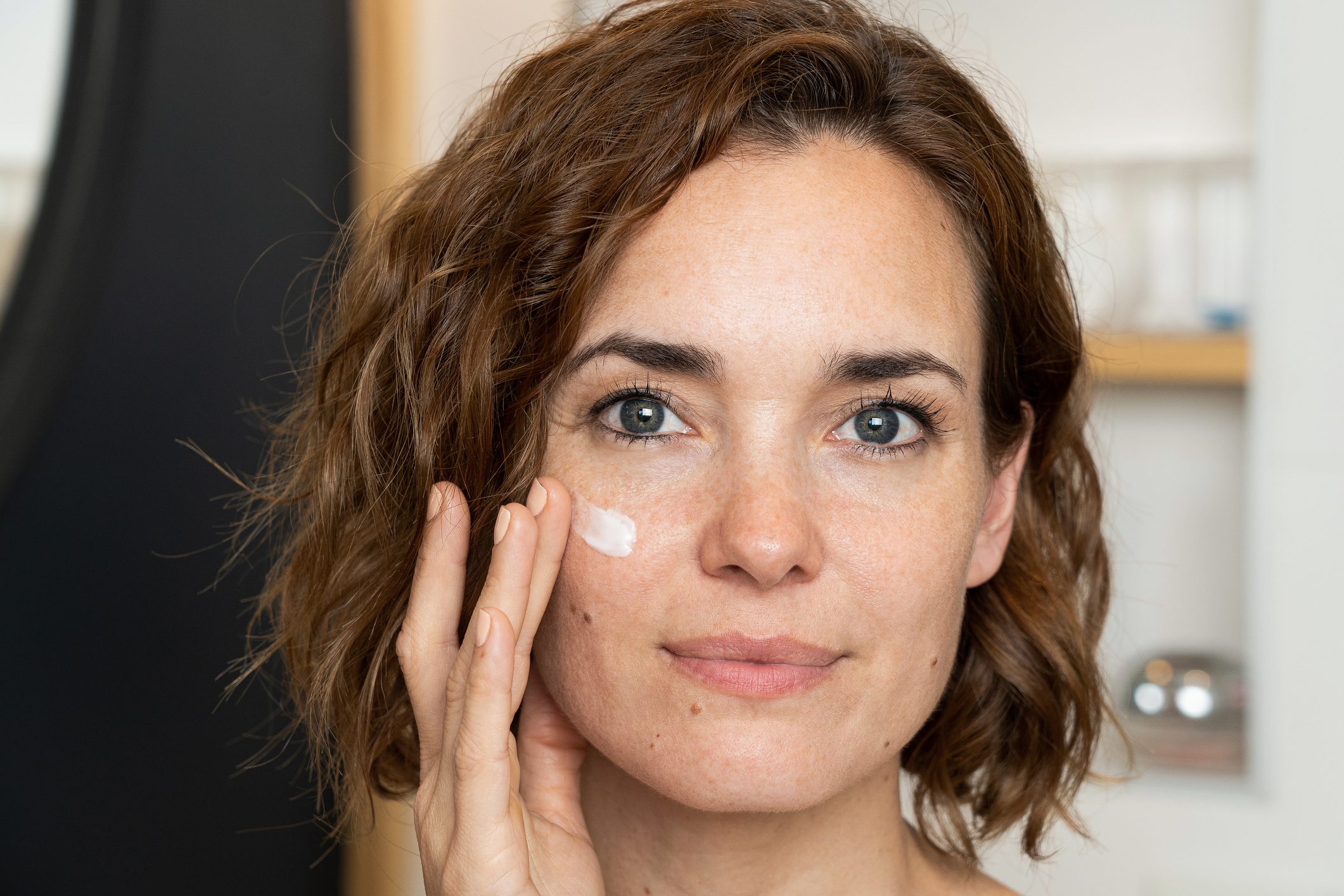 Close-up of woman applying cream on her face