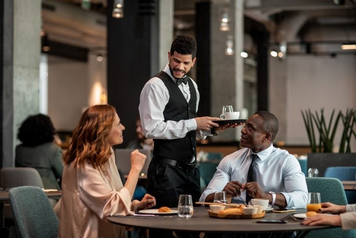 Group of business people ordering food and drinks from the waiter