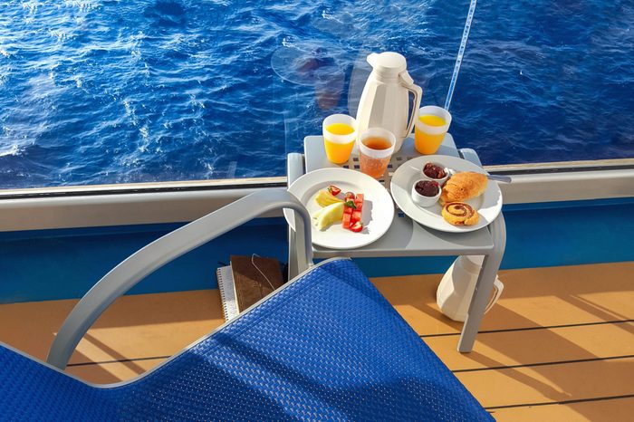 A colorful continental breakfast served on a balcony of a cruise ship at sea, with fruit, juice, breads and coffee.