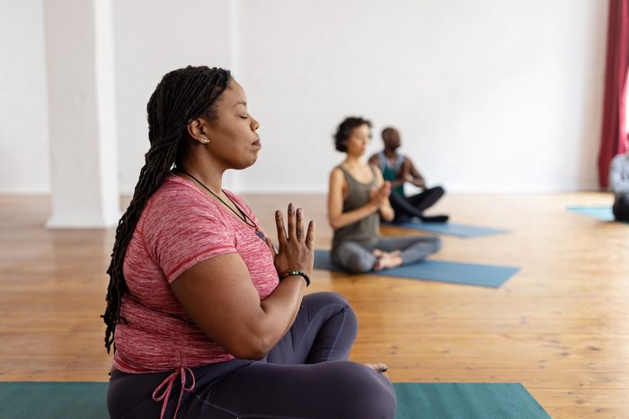 Plus size african woman practicing meditation exercise during yoga class