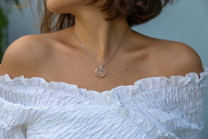 Closed up of trendy woman outfit wearing white shirt and heart shape neckless.