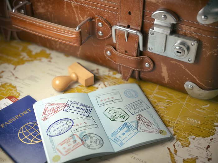 Old suitcase with opened passport and visa stamps
