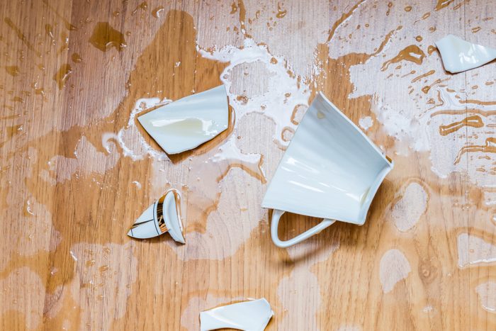 Broken cup with spilled tea on a floor