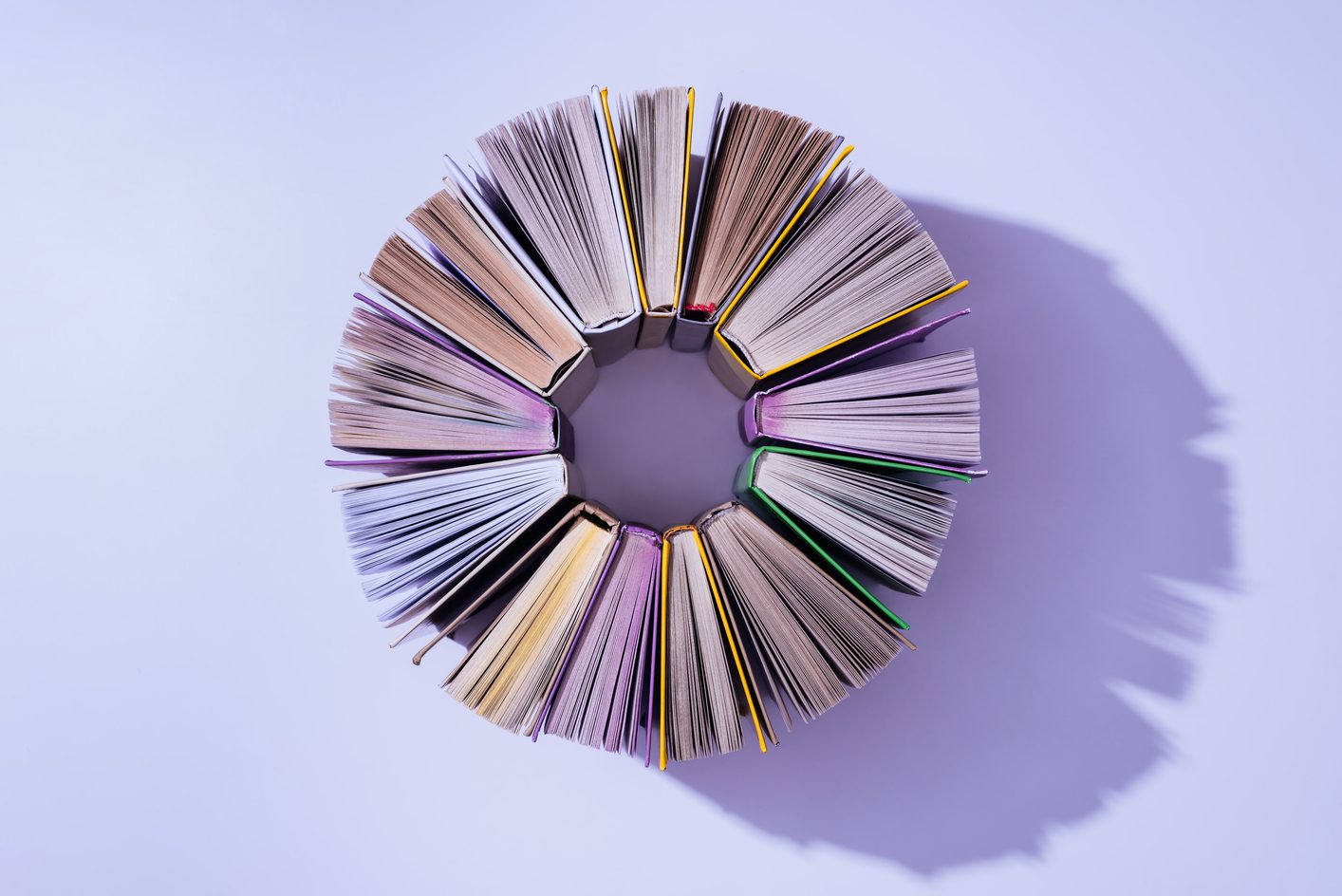 top view of stack of books in circle on violet tabletop