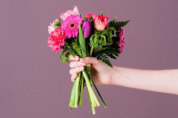 anonymous arm and hand Holding Bunch Of Flowers for an apology