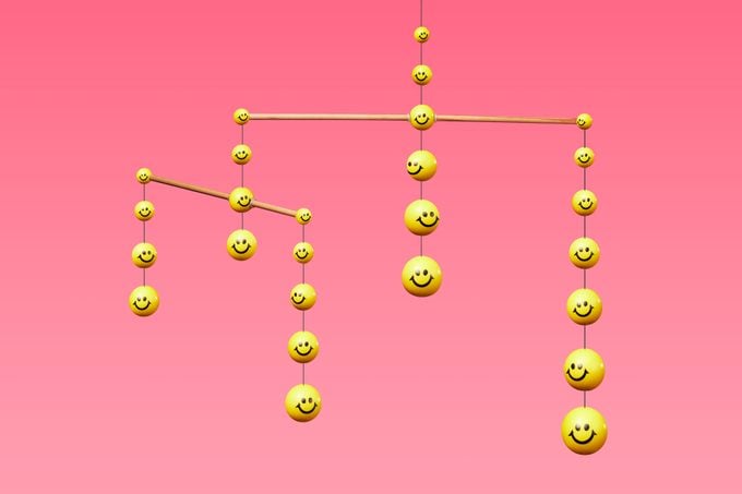 mobile made up of yellow smiley faces on pink background to represent community and support network for a happier life