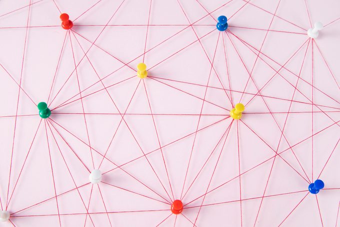 Network Of colorful pins connected by string on pink background