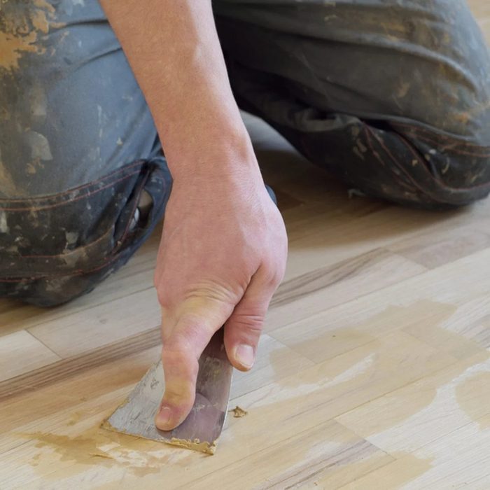 Person using a chisel to add in wood filler before finishing the new floors