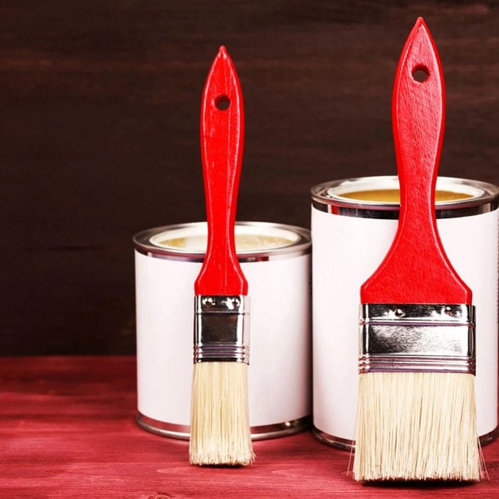 Red paintbrushes in front of white paint cans getting ready to stain a floor