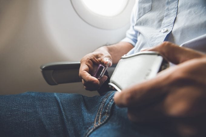 Passenger fastening seat belt while sitting on the airplane