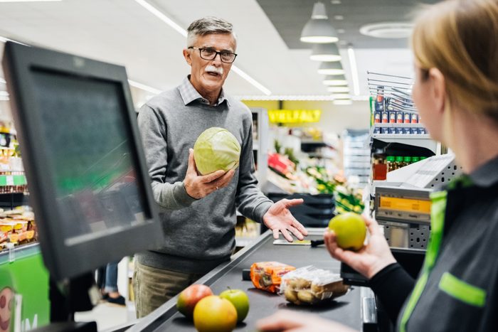 Senior Man Holding Melon And Talking To Cashier