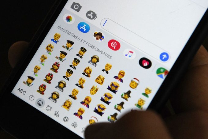 Person holding an iPhone shows emojis on keyboard in texting application