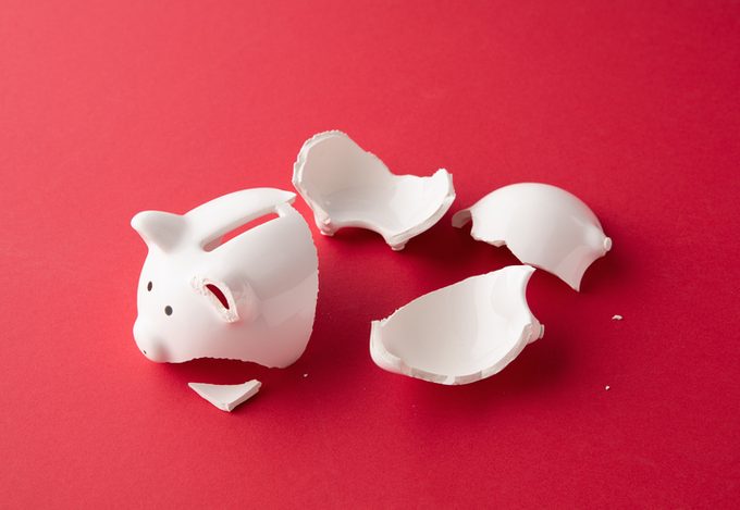 Broken white ceramic piggy bank on a red background