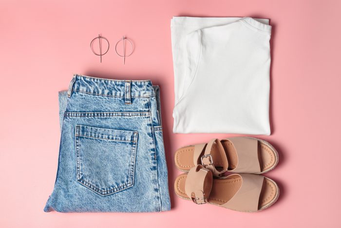 Set of women's fashion for the summer, the view from above. Jeans, white T-shirt, bag and sandals on pink background