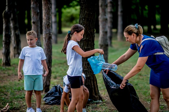 School children picking up garbage together while cleaning public park