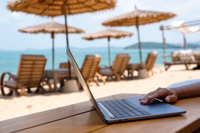 a woman working and touching on laptop touchpad on the beach