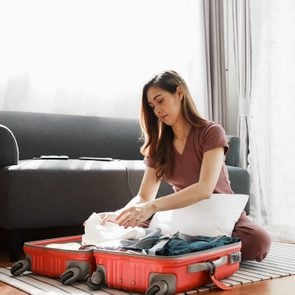 Woman Packing Suitcase At Home