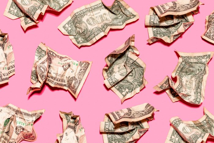 Pattern of crumpled one dollar bills lying against pink background